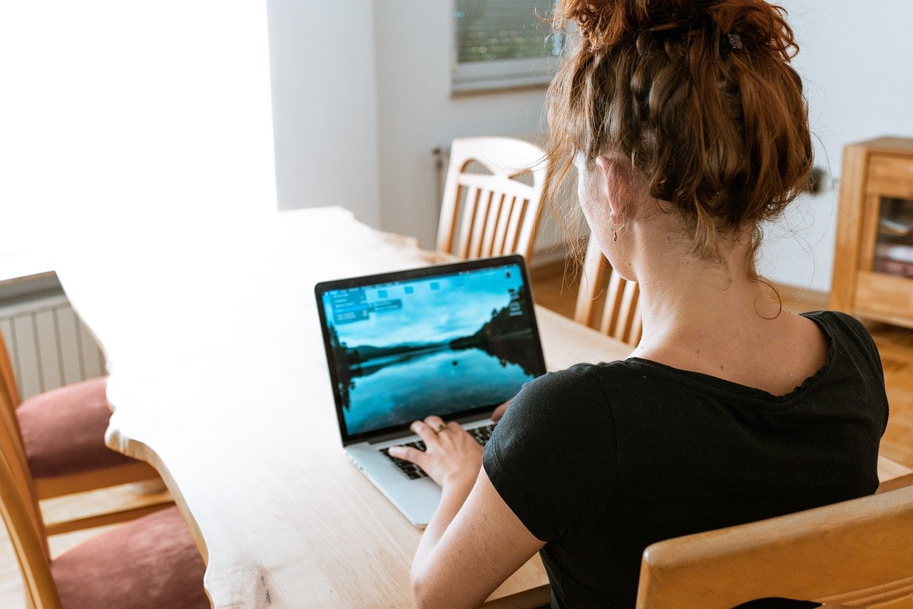 Symbolbild Frau sitzt am Küchentisch mit Laptop im Homeoffice